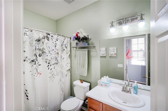 bathroom featuring vanity, walk in shower, and toilet
