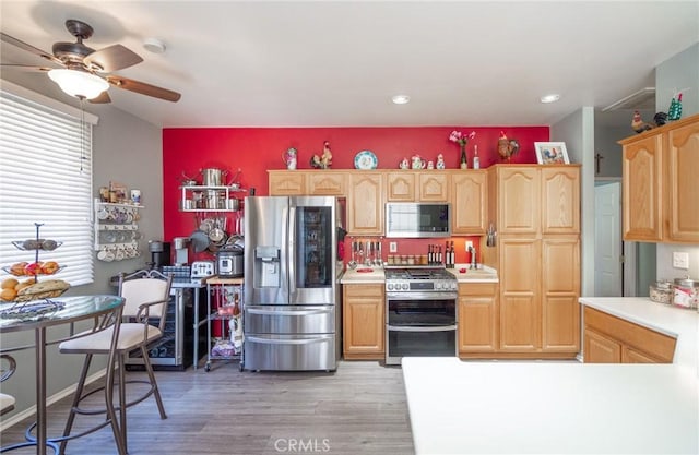kitchen with ceiling fan, appliances with stainless steel finishes, light brown cabinetry, and light wood-type flooring