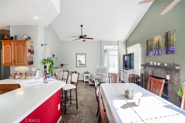 kitchen with a fireplace, lofted ceiling, a kitchen breakfast bar, and sink