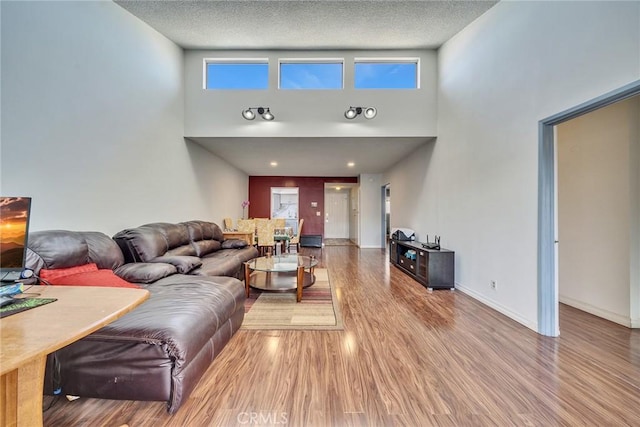 living room featuring a high ceiling, wood-type flooring, and a textured ceiling