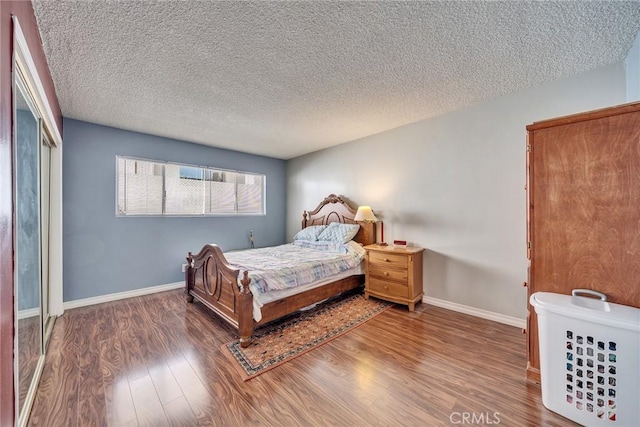 bedroom with a textured ceiling, baseboards, and wood finished floors