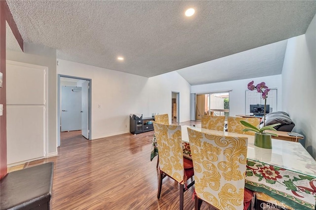 dining room with a textured ceiling, recessed lighting, wood finished floors, baseboards, and vaulted ceiling