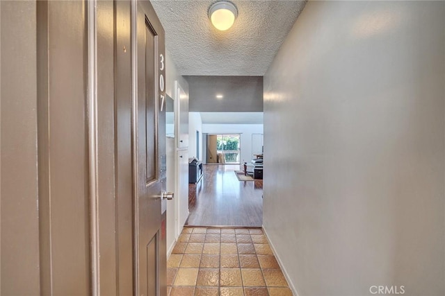 hall with light tile patterned floors and a textured ceiling