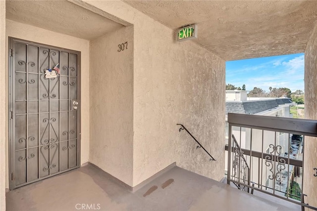 property entrance with a balcony and stucco siding