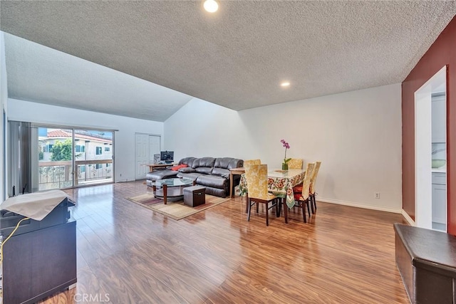 living area with a textured ceiling, baseboards, and wood finished floors