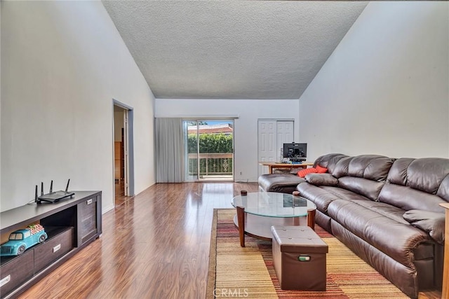 living area featuring a textured ceiling, high vaulted ceiling, and wood finished floors