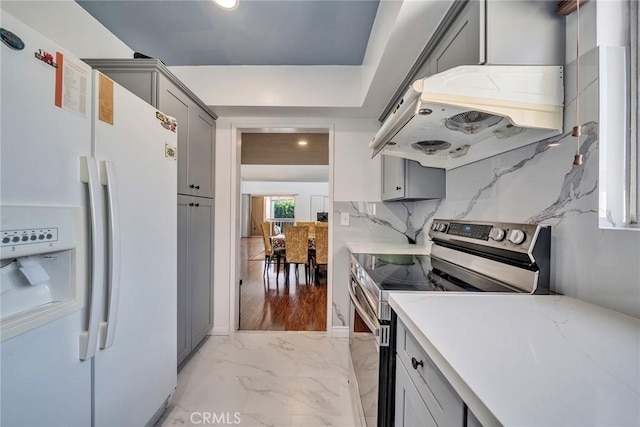 kitchen with marble finish floor, gray cabinetry, stainless steel range with electric cooktop, white fridge with ice dispenser, and under cabinet range hood