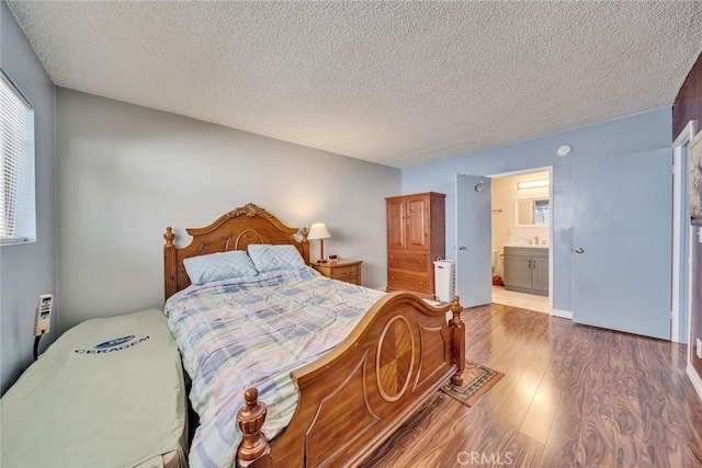 bedroom with wood-type flooring, sink, ensuite bathroom, and a textured ceiling