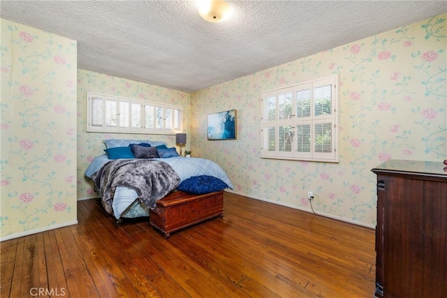 bedroom featuring dark hardwood / wood-style flooring, a textured ceiling, and multiple windows