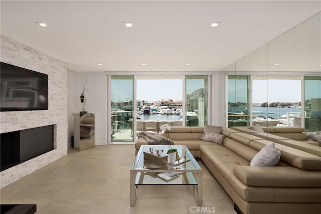 living room with floor to ceiling windows, a water view, and a fireplace