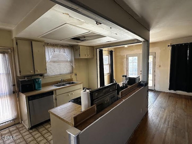 kitchen with light hardwood / wood-style floors, stainless steel dishwasher, cream cabinetry, and sink