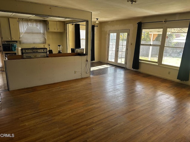 unfurnished living room featuring a wealth of natural light, hardwood / wood-style floors, and french doors