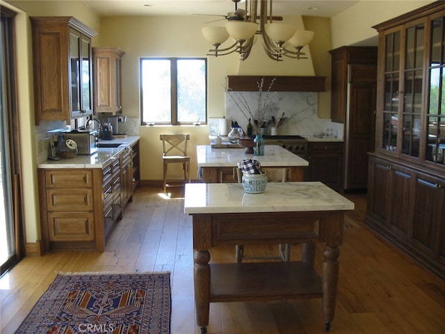 kitchen featuring hardwood / wood-style flooring, a notable chandelier, backsplash, and a center island