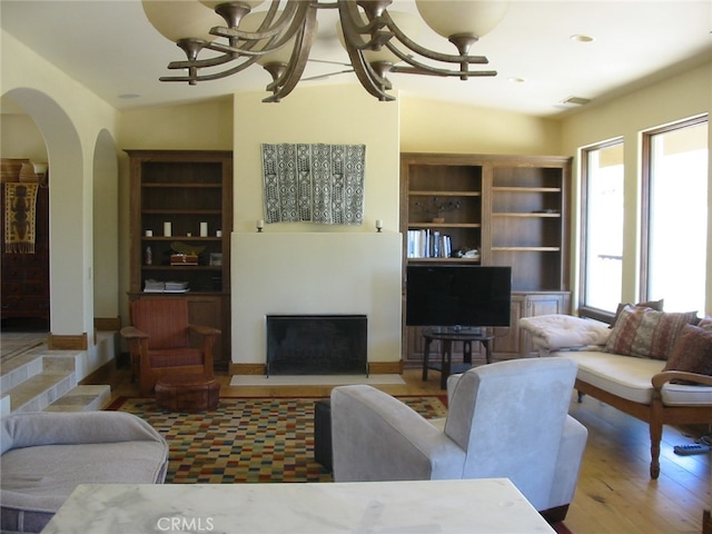 living room with lofted ceiling, light wood-type flooring, and a notable chandelier