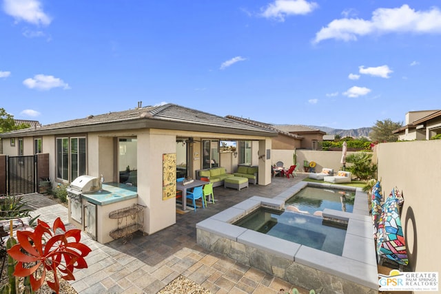 back of house featuring an outdoor living space, area for grilling, a mountain view, a swimming pool with hot tub, and a patio