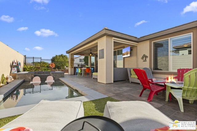 view of patio / terrace with ceiling fan, a fenced in pool, and a fire pit