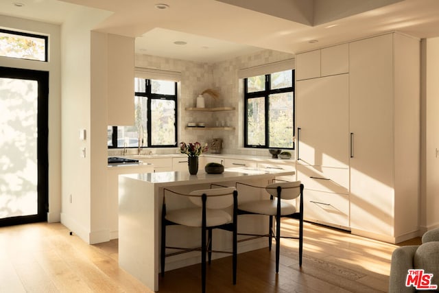 kitchen with white cabinetry, light hardwood / wood-style floors, a breakfast bar, and a center island