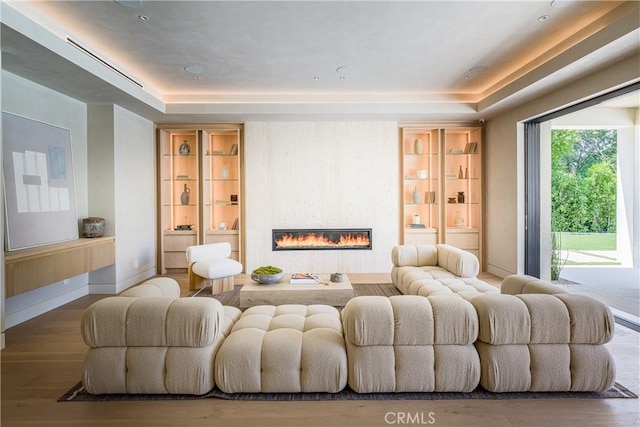 cinema room with hardwood / wood-style flooring, a large fireplace, and a tray ceiling