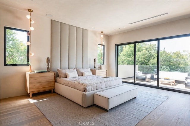 bedroom featuring light hardwood / wood-style floors, multiple windows, and access to outside