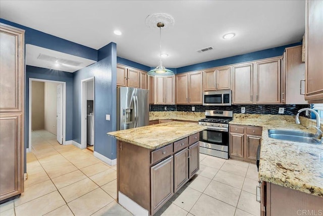 kitchen featuring light stone countertops, sink, a center island, and appliances with stainless steel finishes