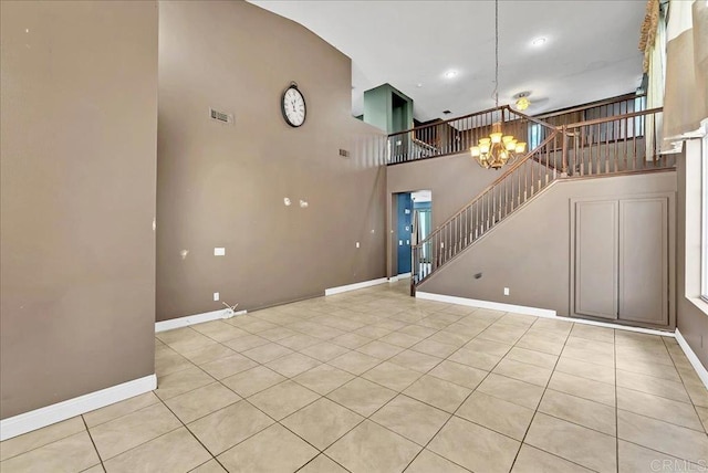 unfurnished living room featuring a chandelier, a towering ceiling, and light tile patterned flooring