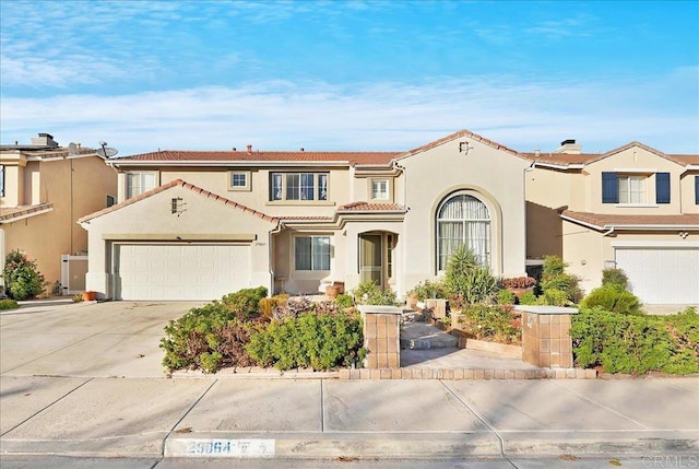 mediterranean / spanish home with stucco siding, an attached garage, driveway, and a tile roof