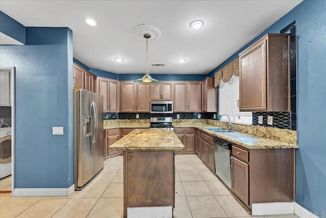 kitchen featuring visible vents, a center island, washer / dryer, stainless steel appliances, and a sink