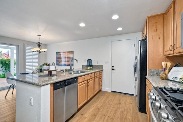 kitchen with kitchen peninsula, hanging light fixtures, light wood-type flooring, appliances with stainless steel finishes, and sink