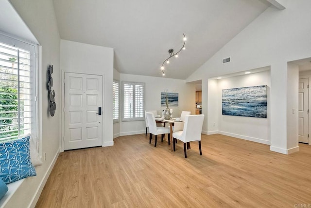 dining area with a healthy amount of sunlight, light wood-type flooring, and vaulted ceiling