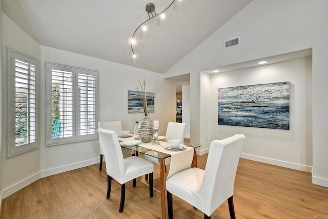 dining area with light wood-type flooring and vaulted ceiling