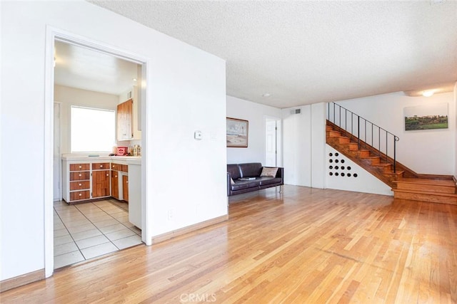 unfurnished living room with a textured ceiling and light hardwood / wood-style flooring