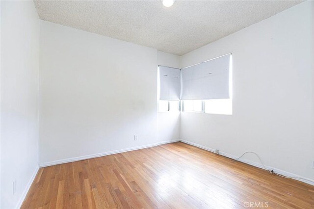 spare room with a textured ceiling and light wood-type flooring