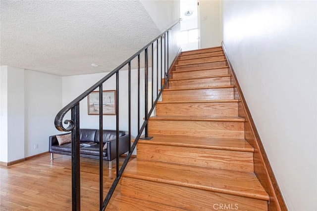 stairs with a textured ceiling and hardwood / wood-style floors