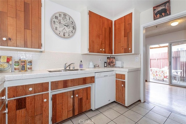 kitchen featuring light tile patterned floors, dishwasher, tasteful backsplash, and sink