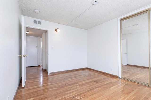 unfurnished bedroom with a closet, a textured ceiling, and hardwood / wood-style floors