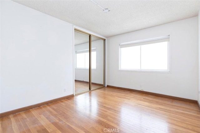 unfurnished bedroom with a closet, a textured ceiling, and light hardwood / wood-style floors