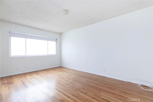 empty room with wood-type flooring and a textured ceiling