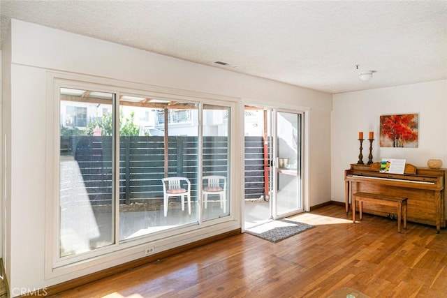 doorway with a textured ceiling and light hardwood / wood-style flooring