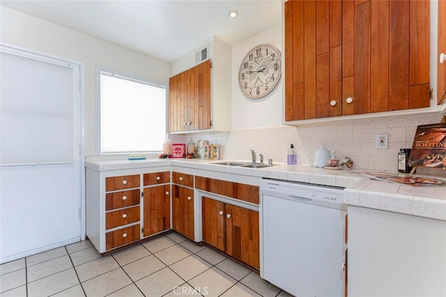 kitchen with dishwasher, decorative backsplash, sink, light tile patterned flooring, and tile counters