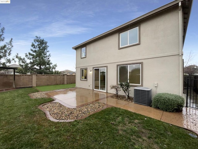 rear view of property featuring central air condition unit, a lawn, and a patio