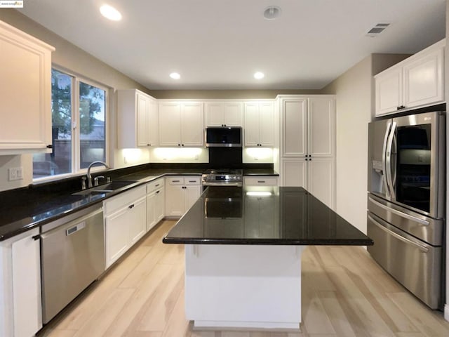 kitchen featuring a kitchen island, sink, light wood-type flooring, stainless steel appliances, and white cabinets