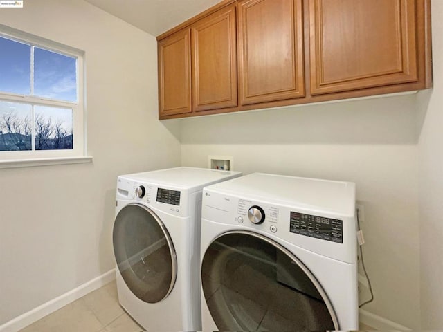 clothes washing area featuring washer and dryer, cabinets, and light tile patterned floors