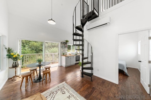 staircase featuring a wall mounted AC, a towering ceiling, and hardwood / wood-style floors