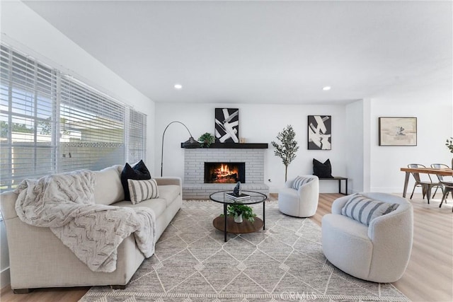 living room with a brick fireplace and hardwood / wood-style flooring