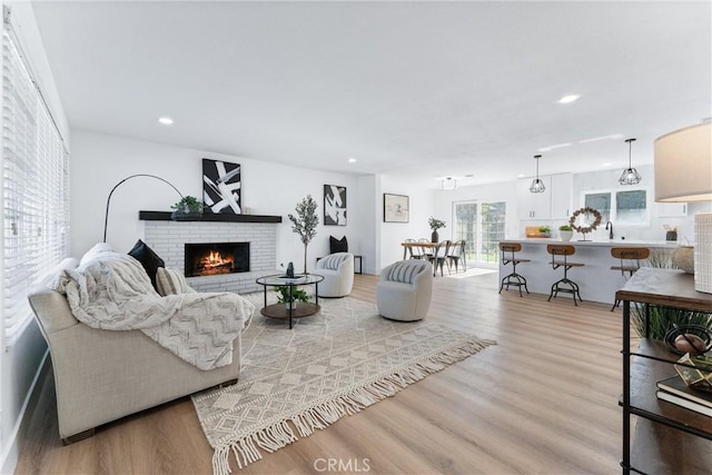 living room featuring light wood-type flooring, a brick fireplace, and sink