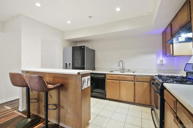 kitchen with light tile patterned flooring, appliances with stainless steel finishes, sink, and a kitchen bar