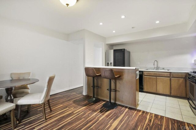 kitchen with sink, stainless steel fridge, dishwasher, kitchen peninsula, and light hardwood / wood-style floors