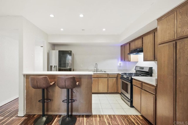 kitchen featuring a breakfast bar, sink, light hardwood / wood-style flooring, appliances with stainless steel finishes, and kitchen peninsula