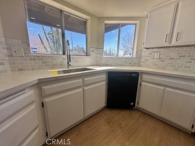 kitchen featuring backsplash, dishwasher, sink, light hardwood / wood-style flooring, and white cabinets