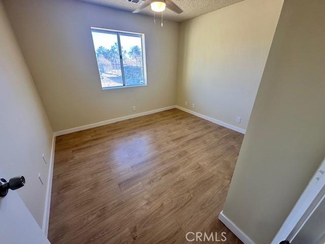 unfurnished room with ceiling fan, a textured ceiling, and hardwood / wood-style floors